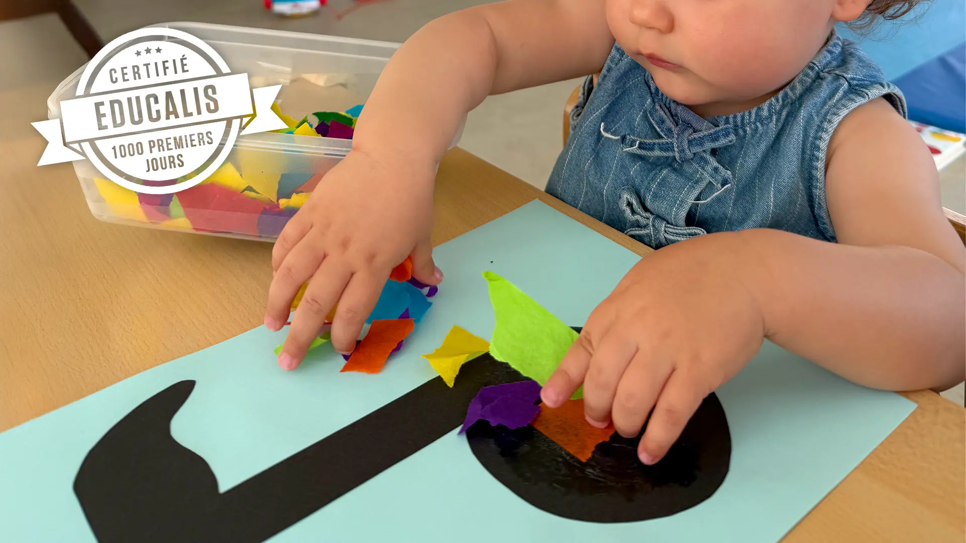 Enfant de la Nurserie collant du papier coloré sur une note de musique à la crèche 6 Sens à Saint-Sulpice.
