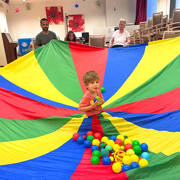 Enfants de la crèche 6 Sens et résidents de l’EMS de Sauvabelin partageant une séance de gym avec parachute