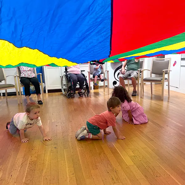 Enfants de la crèche 6 Sens et résidents de l’EMS de Sauvabelin partageant une séance de gym avec parachute